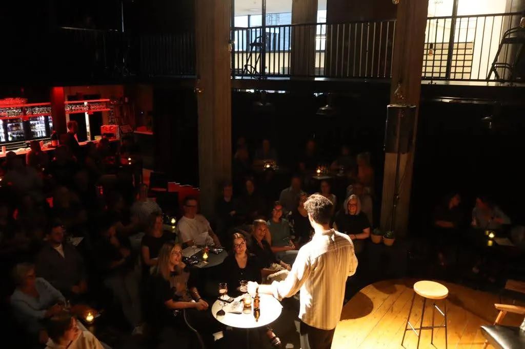 A comedian performing for a seated audience at MUZEcafé in Heusden-Zolder.