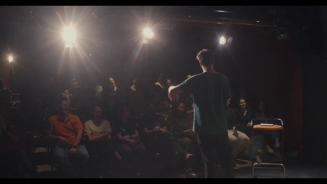 A performer facing the audience under the stage lights at Theater Box in Ghent.